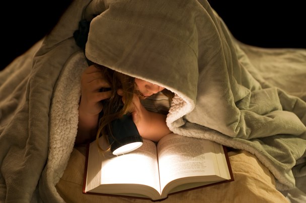 Девочка читает под одеялом